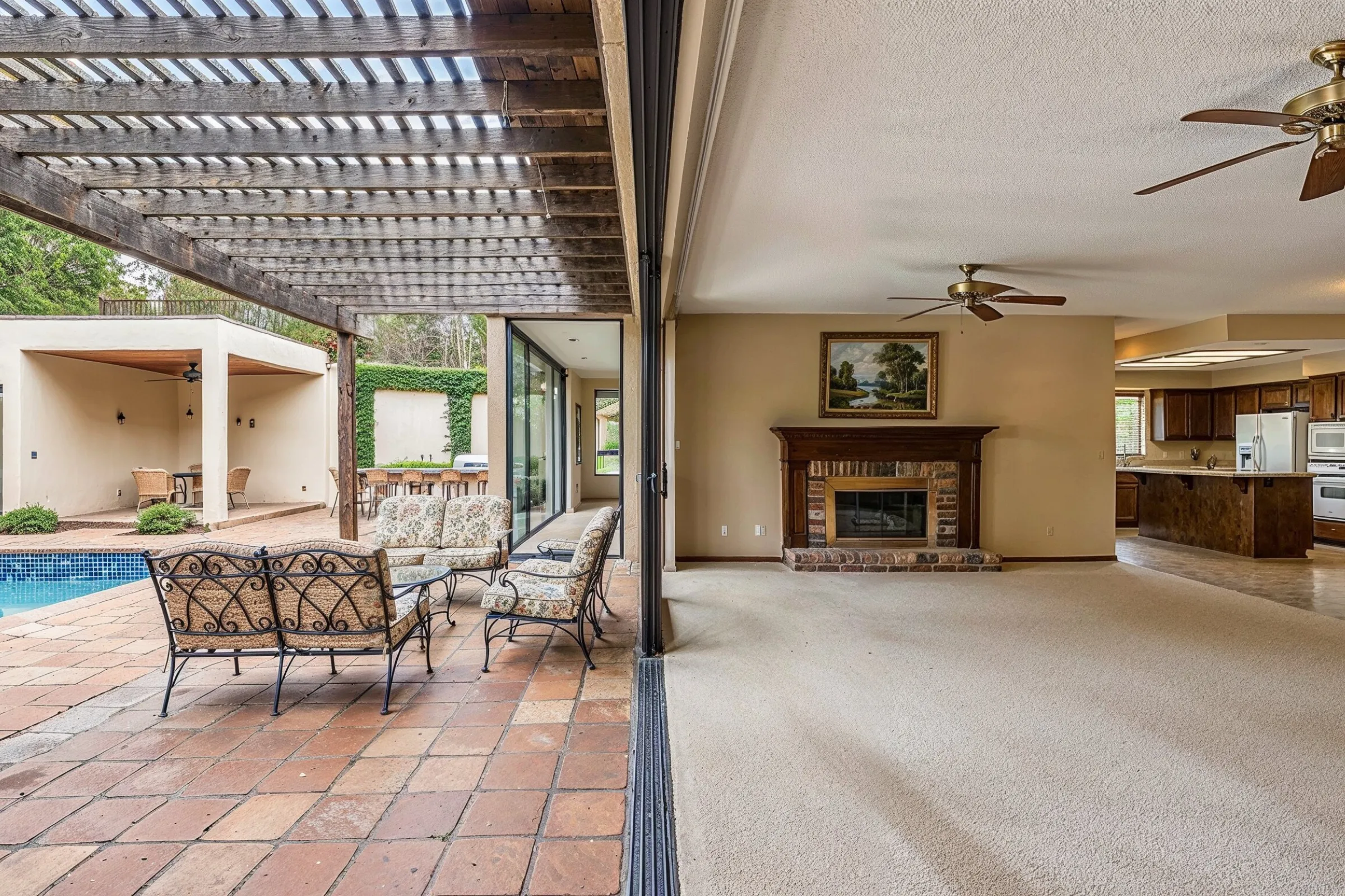Before full-home remodeling project in Los Angeles showing outdated indoor-outdoor living area, older carpet, dated fireplace, older kitchen finishes, patio connection, and disconnected room flow