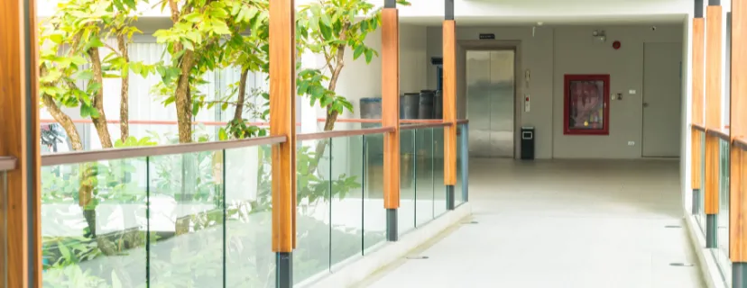 Completed condo remodeling project in Los Angeles with modern common area, glass railings, wood accents, updated finishes, and bright interior walkway